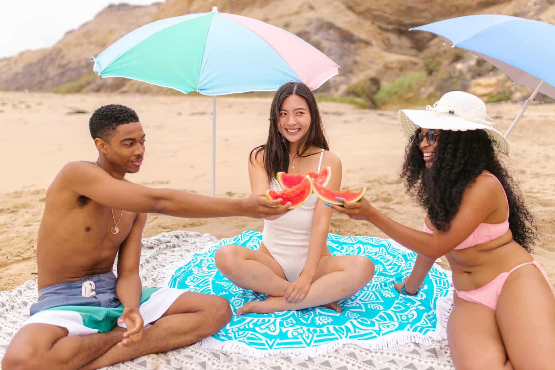 group of friends holding watermelons on the beach